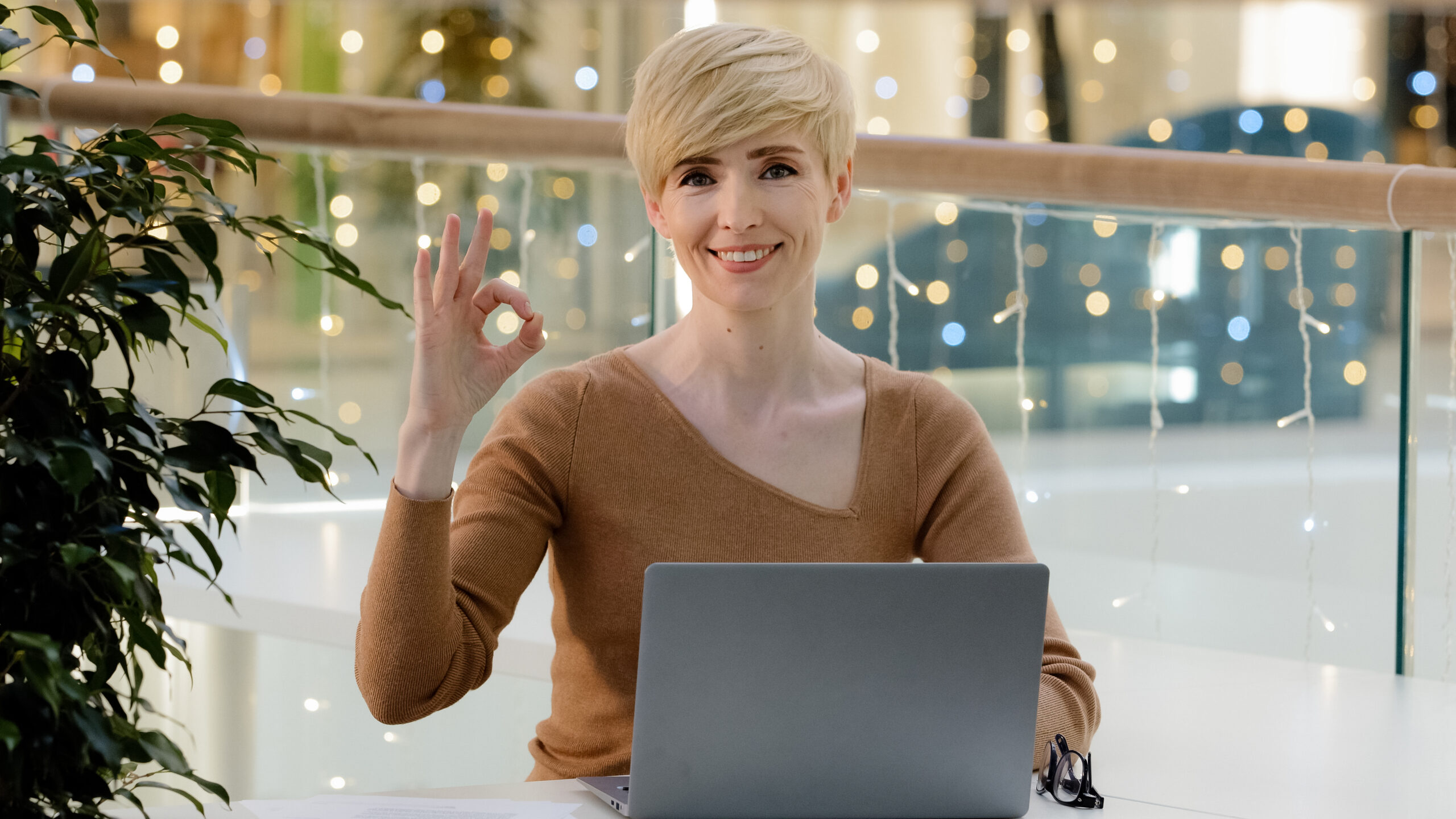 Caucasian business woman adult 40s user teacher coach with laptop typing working online showing ok gesture satisfied with computer app service website recommendation sign promo symbol everything fine Usługi graficzne, social media i strony internetowe